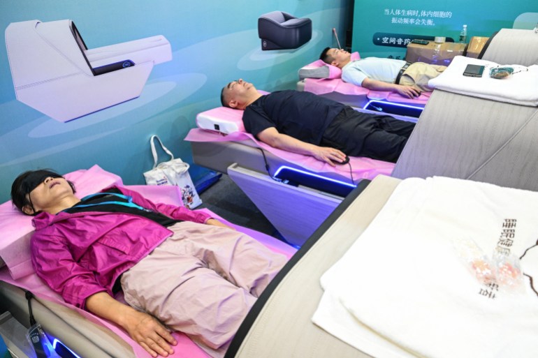 People take a rest as they check a sleep cabin during the International Exhibition of Senior Care, Rehabilitation Medicine and Healthcare (CHINA AID 2024) at the Shanghai New International Expo Centre (SNIEC) in Pudong district of Shanghai on June 13, 2024. (Photo by HECTOR RETAMAL / AFP)