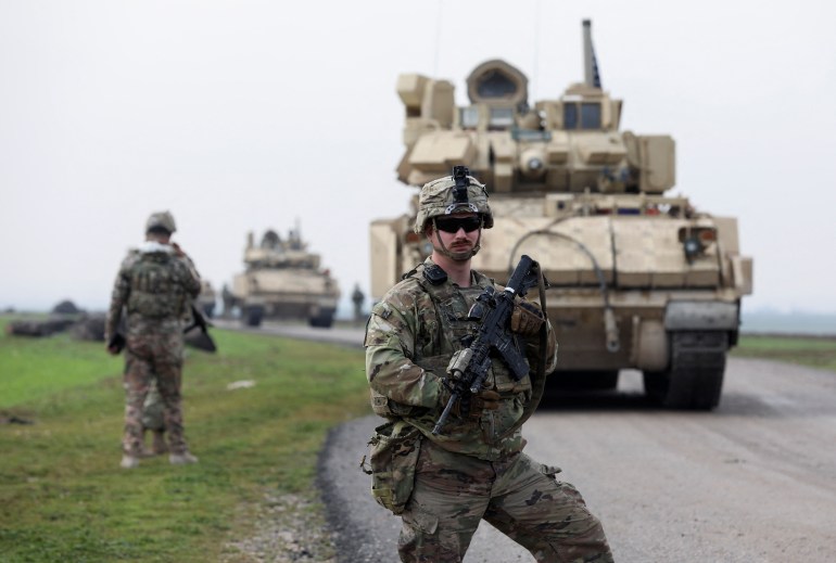 A soldier from the US-led coalition stands guard during a joint U.S.- Kurdish-led Syrian Democratic Forces (SDF) patrol in the countryside of Qamishli in northeastern Syria February 8, 2024. REUTERS/Orhan Qereman